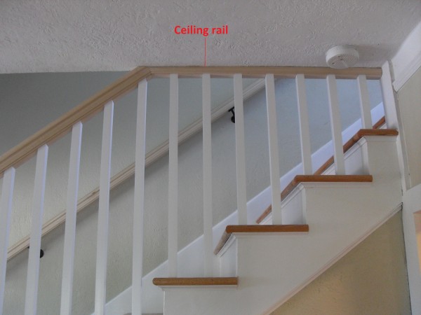 White staircase showing handrail running against ceiling